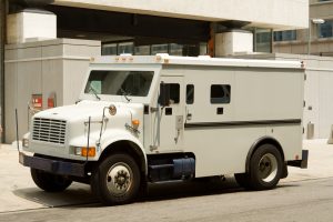 Side view of gray armored truck parked on street making a cash pickup.