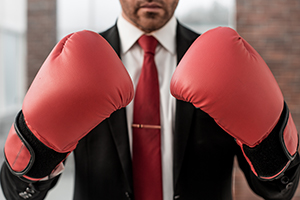 A man in a business suit wearing red boxing gloves